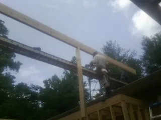 Carpenter setting a ridge beam over a new addition frame — Ice Dam Removal by Roofing Brothers in Spottsville