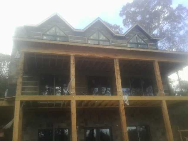 Dormers and porch framing on a large log home under construction — Roof Coating work by our crew in Spottsville