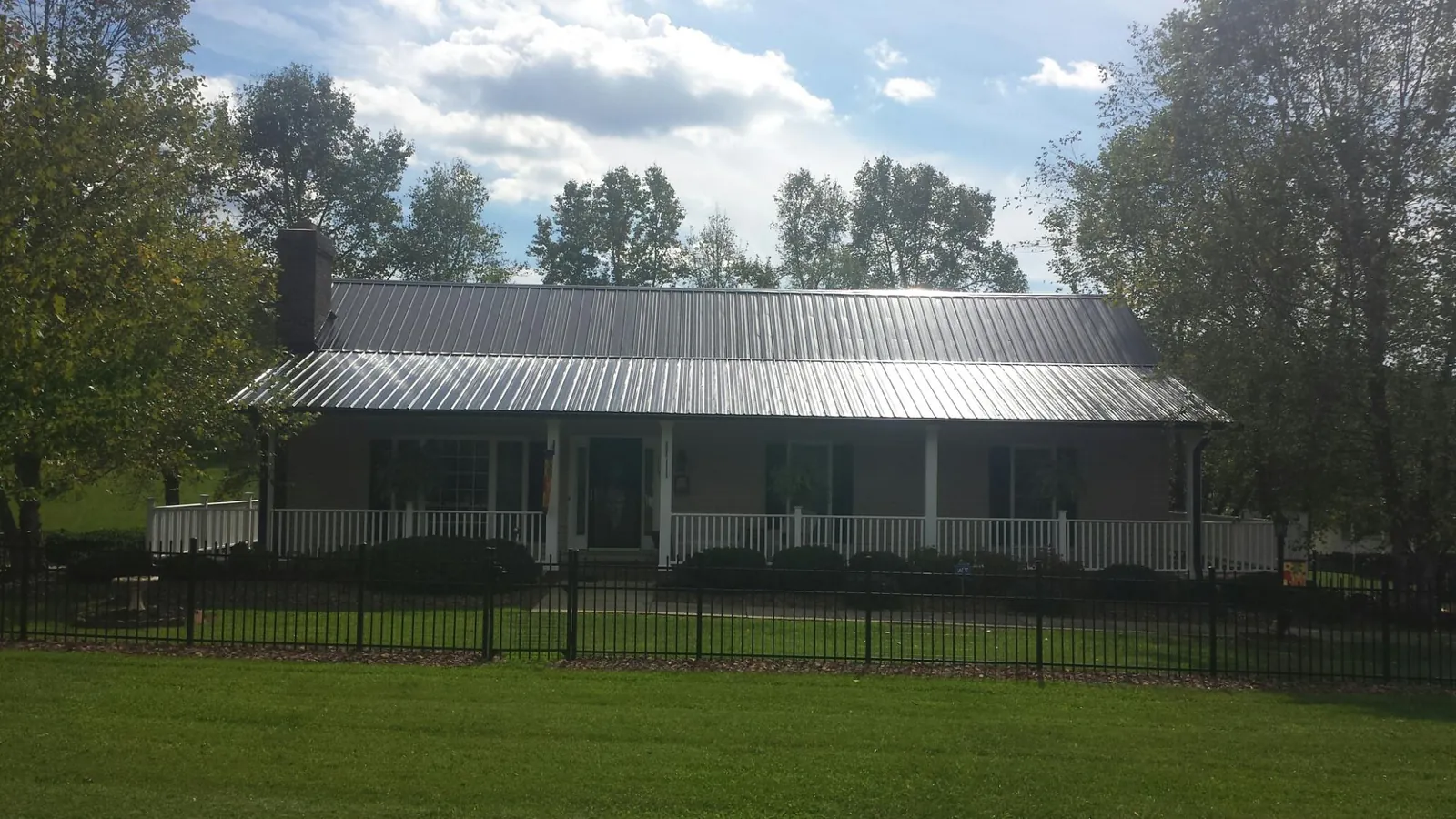Gray metal roof on a brick ranch with a full width front porch — Gutter Guard Installation work by our crew in Spottsville