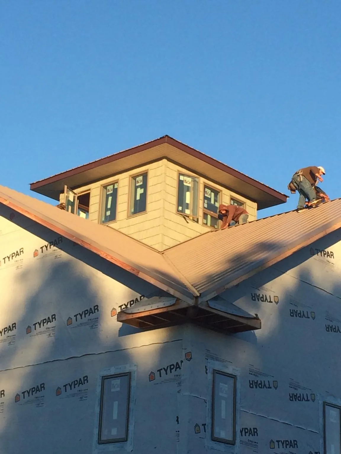 Roofers working around a rooftop cupola on a new metal roof at sunset — Roof Waterproofing in Spottsville by Roofing Brothers